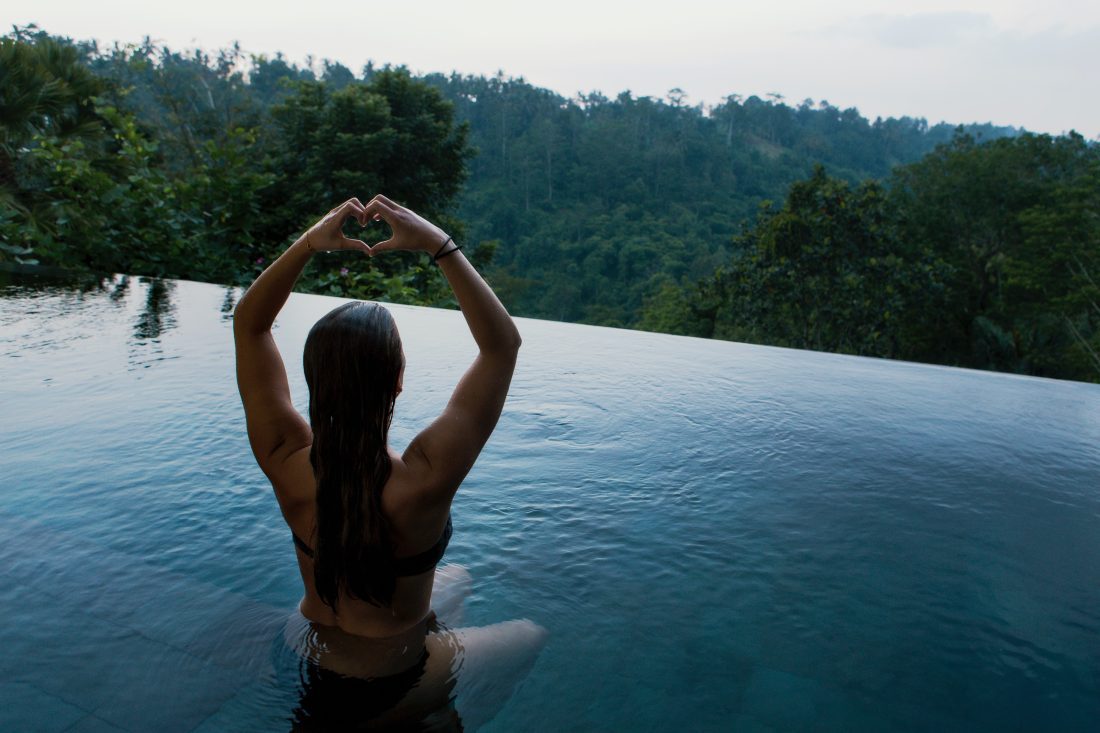 Wellness Journey - Lady in infinity pool looking out over a gorgeous green view
